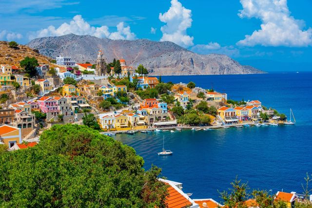 Colorful coastal village on a blue bay with white houses and mountains under a bright sky