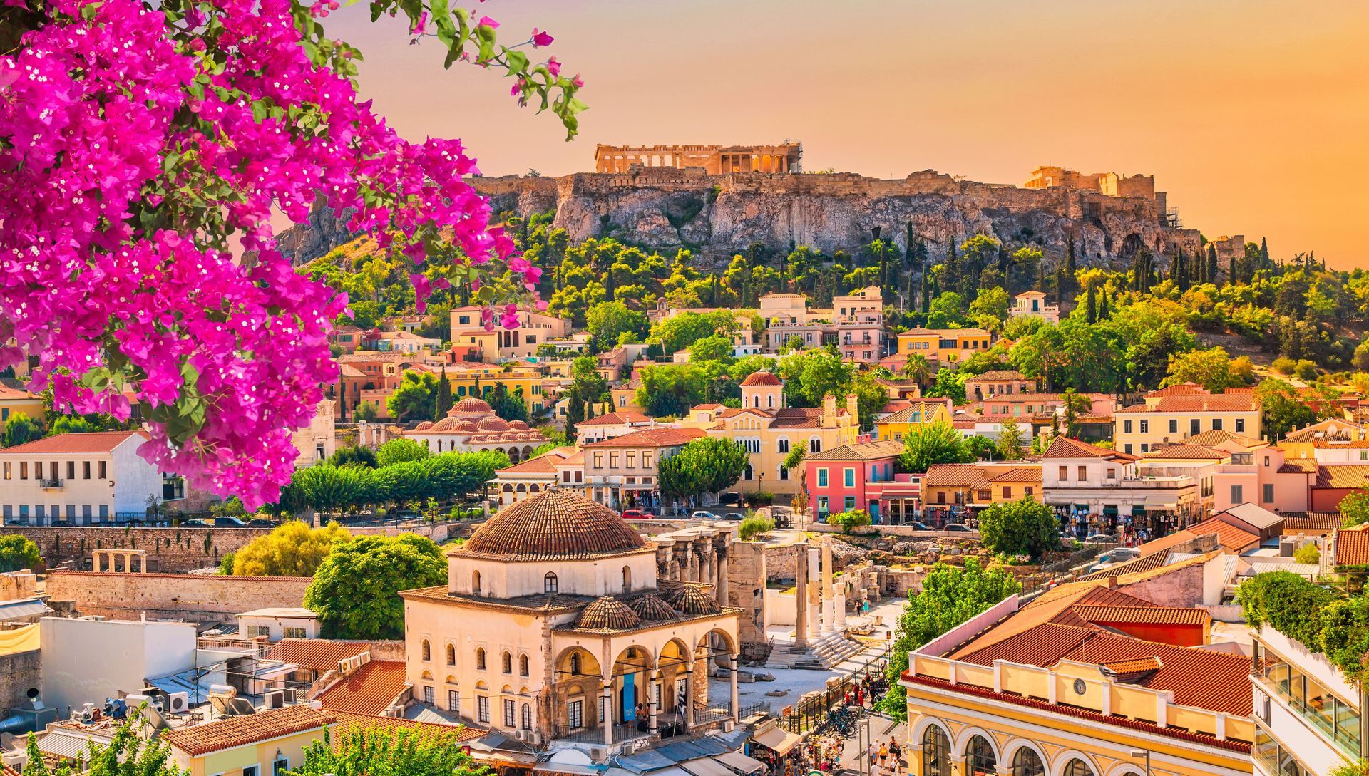 Colorful hillside cityscape with pink bougainvillea and ancient stone buildings under a bright sky