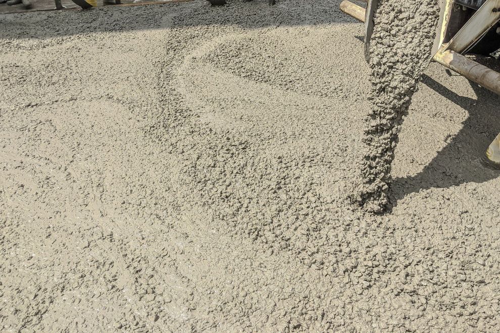 Fresh concrete being poured and smoothed at a construction site