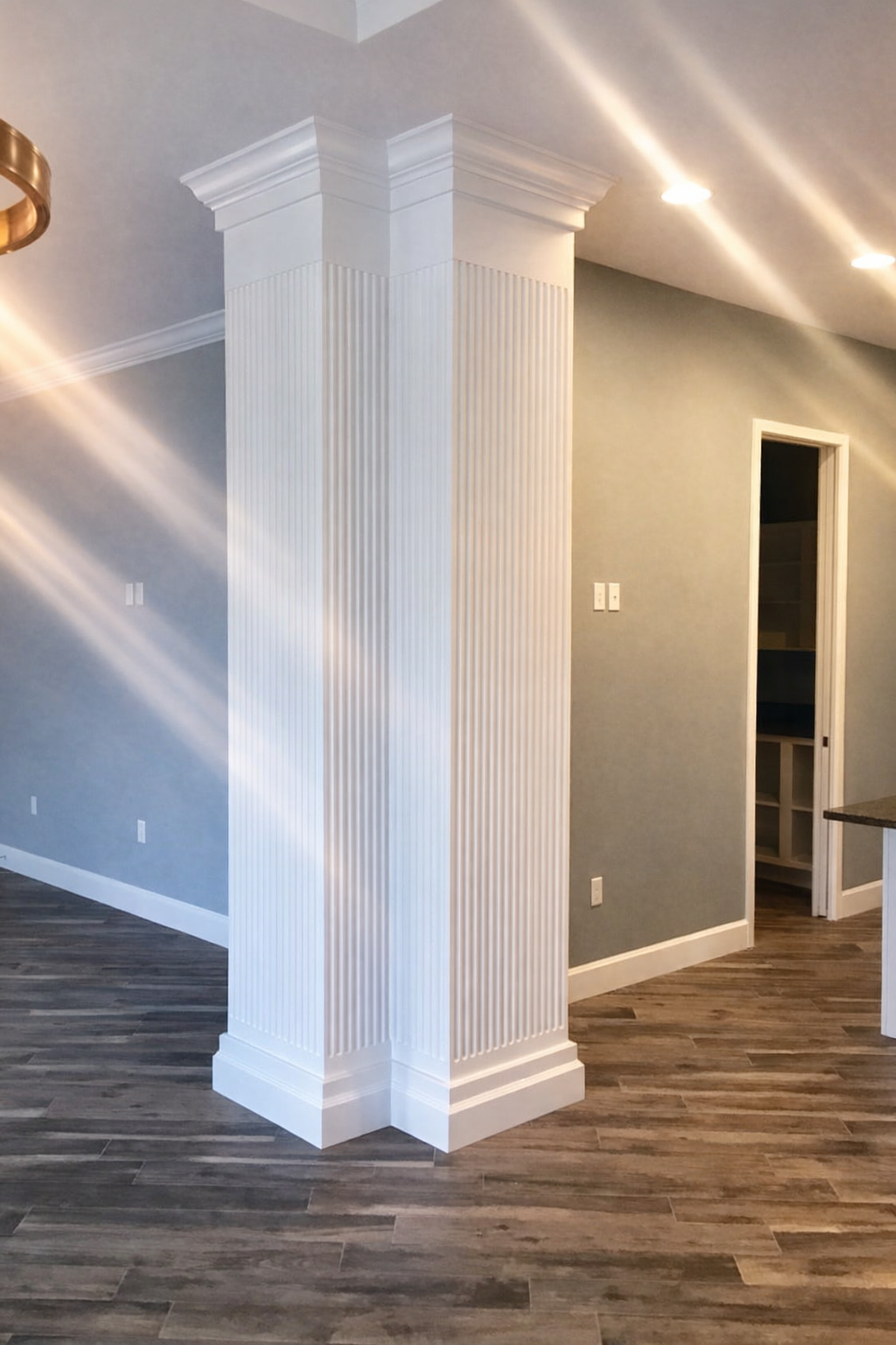 Interior room with gray walls, dark wood floors, and a white decorative column near an open doorway.
