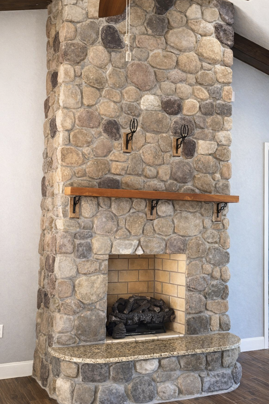 Stone fireplace with a wooden mantel and arched firebox in a living room