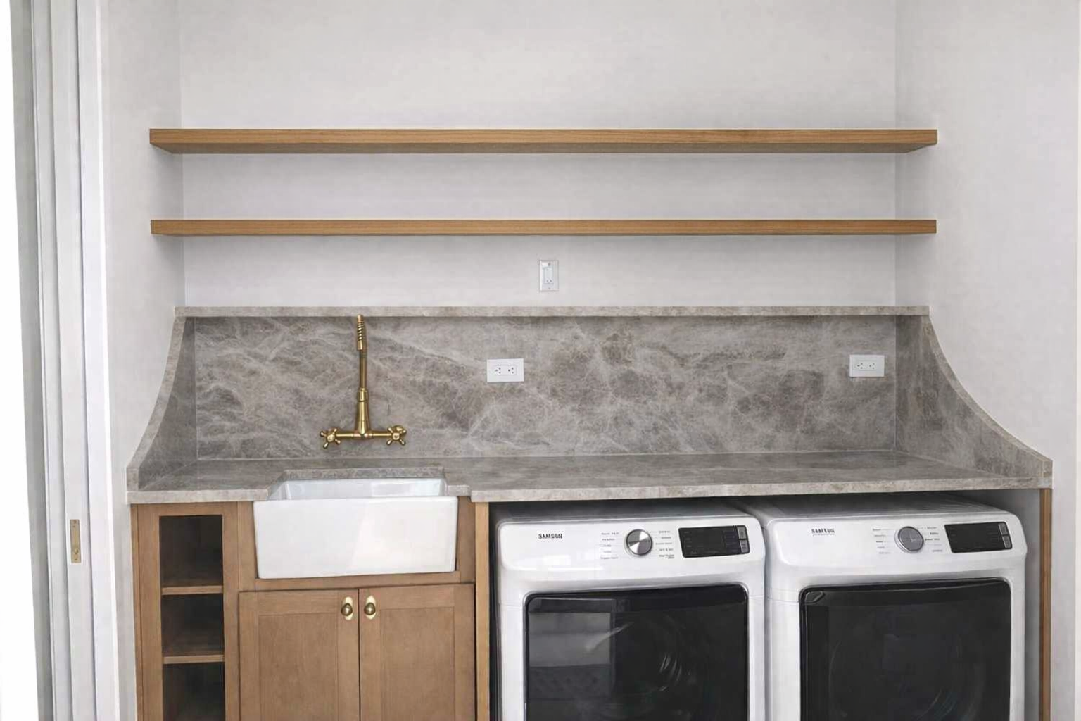 Modern laundry room with gray counter, sink, two wooden shelves, and front-loading washer and dryer