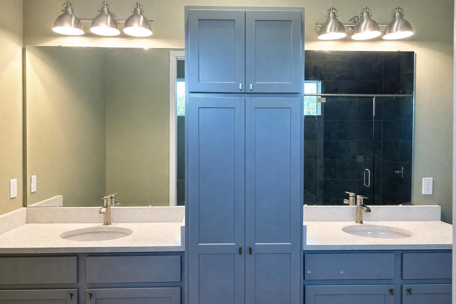 Double vanity bathroom with blue cabinets, large mirrors, and bright overhead lights