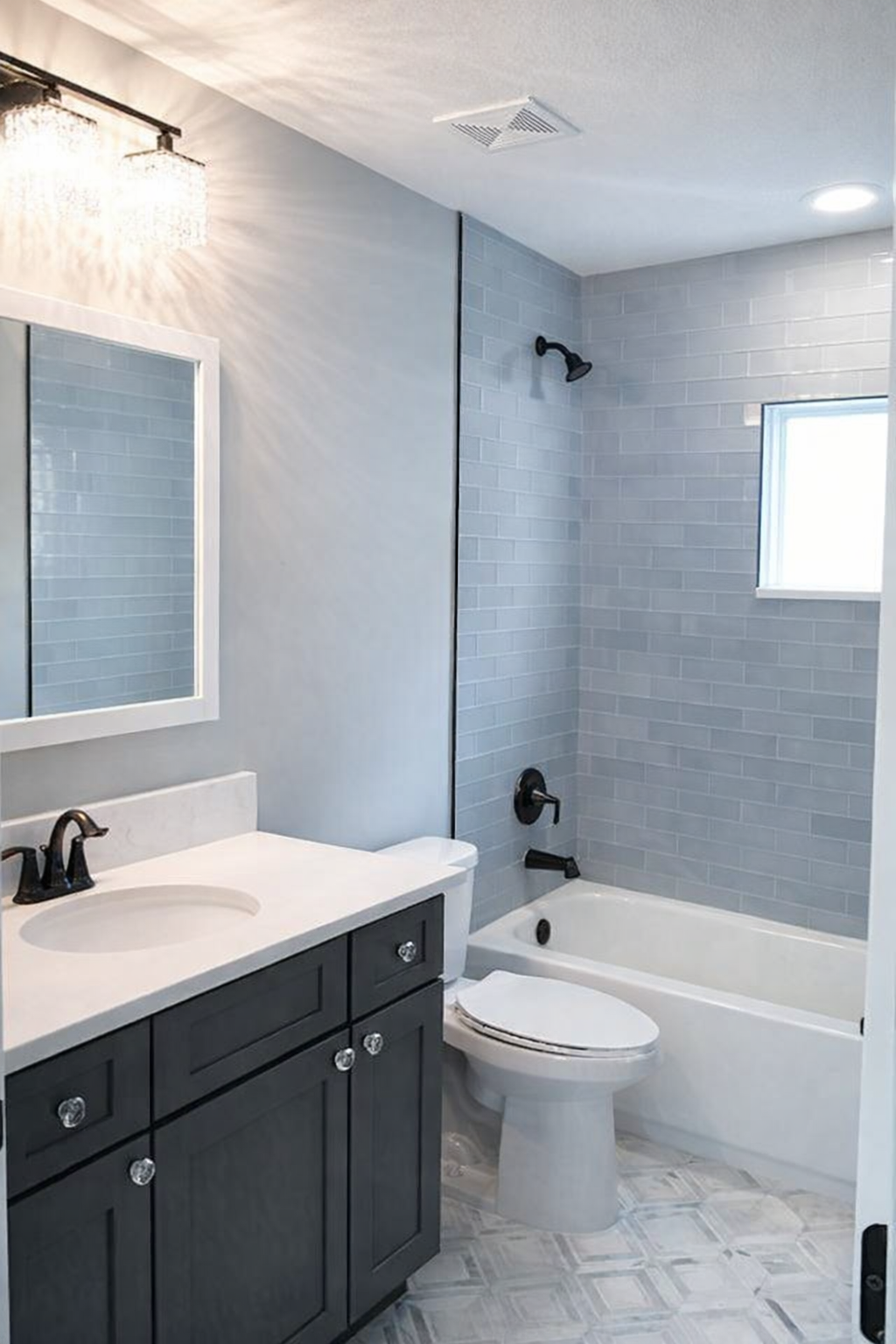 Modern bathroom with gray tile, white tub, toilet, vanity, and mirror