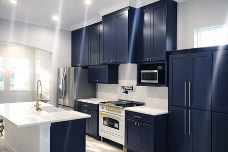 Modern kitchen with dark blue cabinets, stainless steel appliances, and a white island countertop