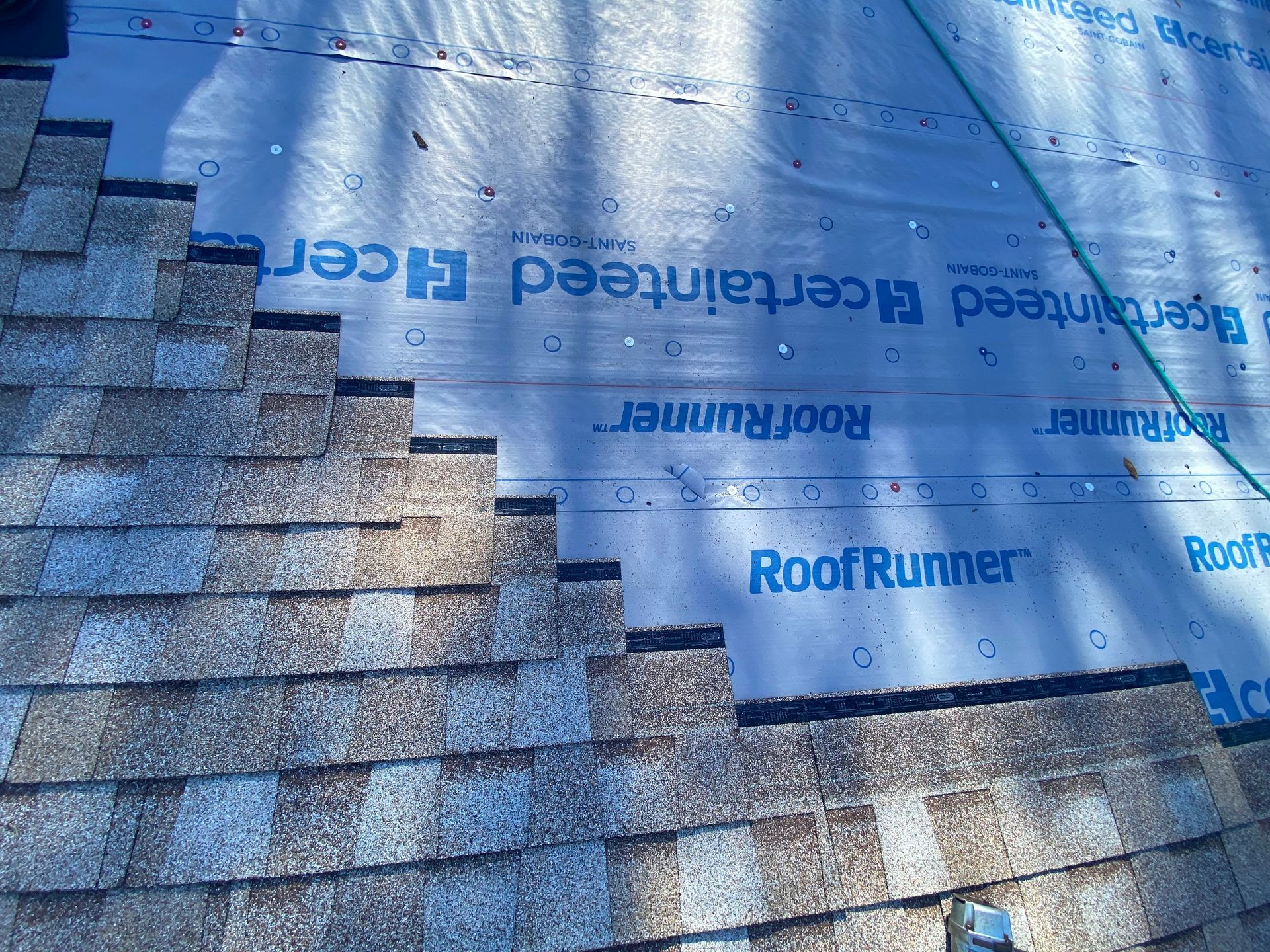 Asphalt shingles being installed on a roof over gray CertainTeed RoofRunner underlayment.