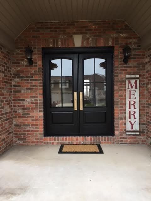Black double doors with gold handles on a brick building,