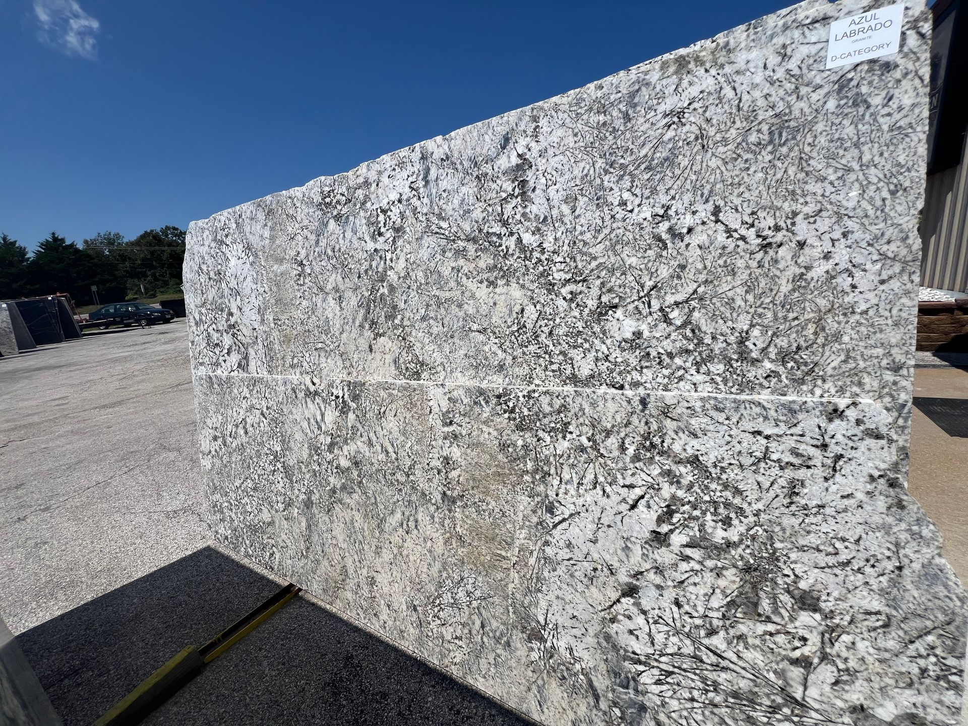Large gray speckled stone slab outdoors under a clear blue sky.