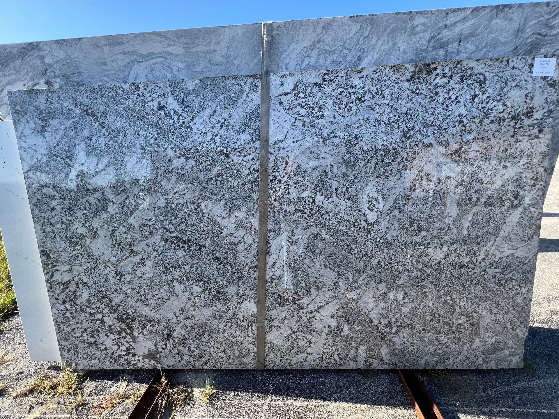 Large gray stone slab with a speckled texture standing outdoors on a metal frame.