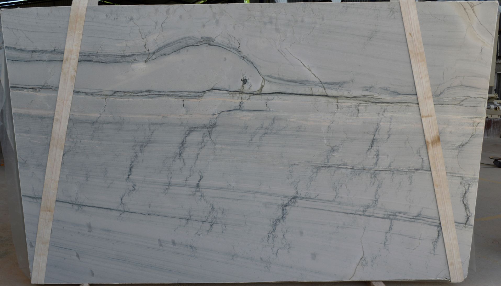 Large gray marble slab with subtle veining and two beige straps across it