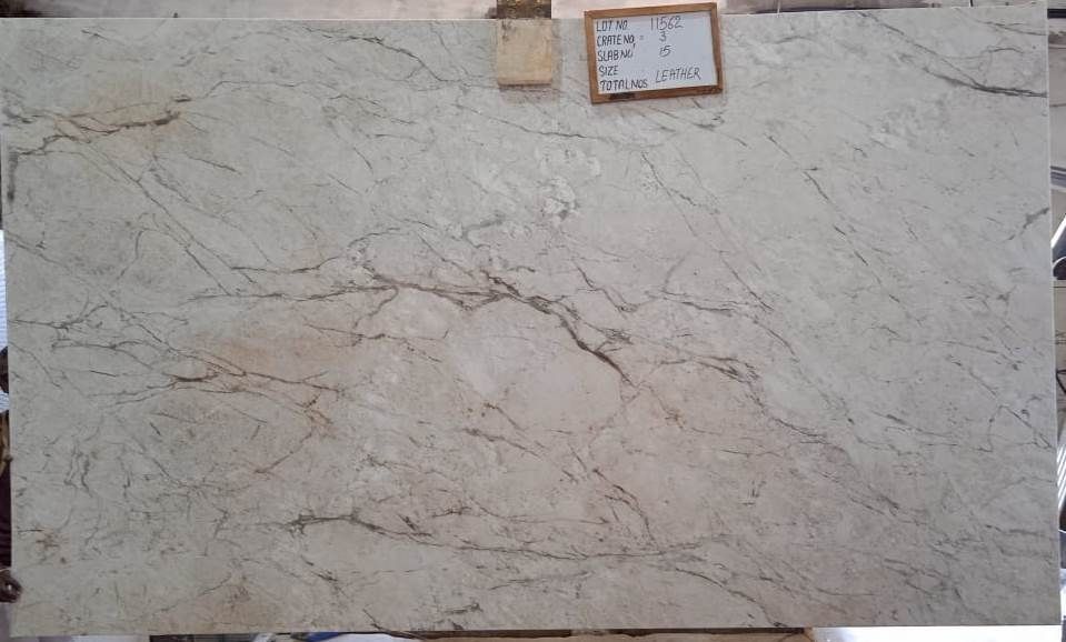 Large light beige marble slab with gray veining, displayed upright with a small price tag at the top