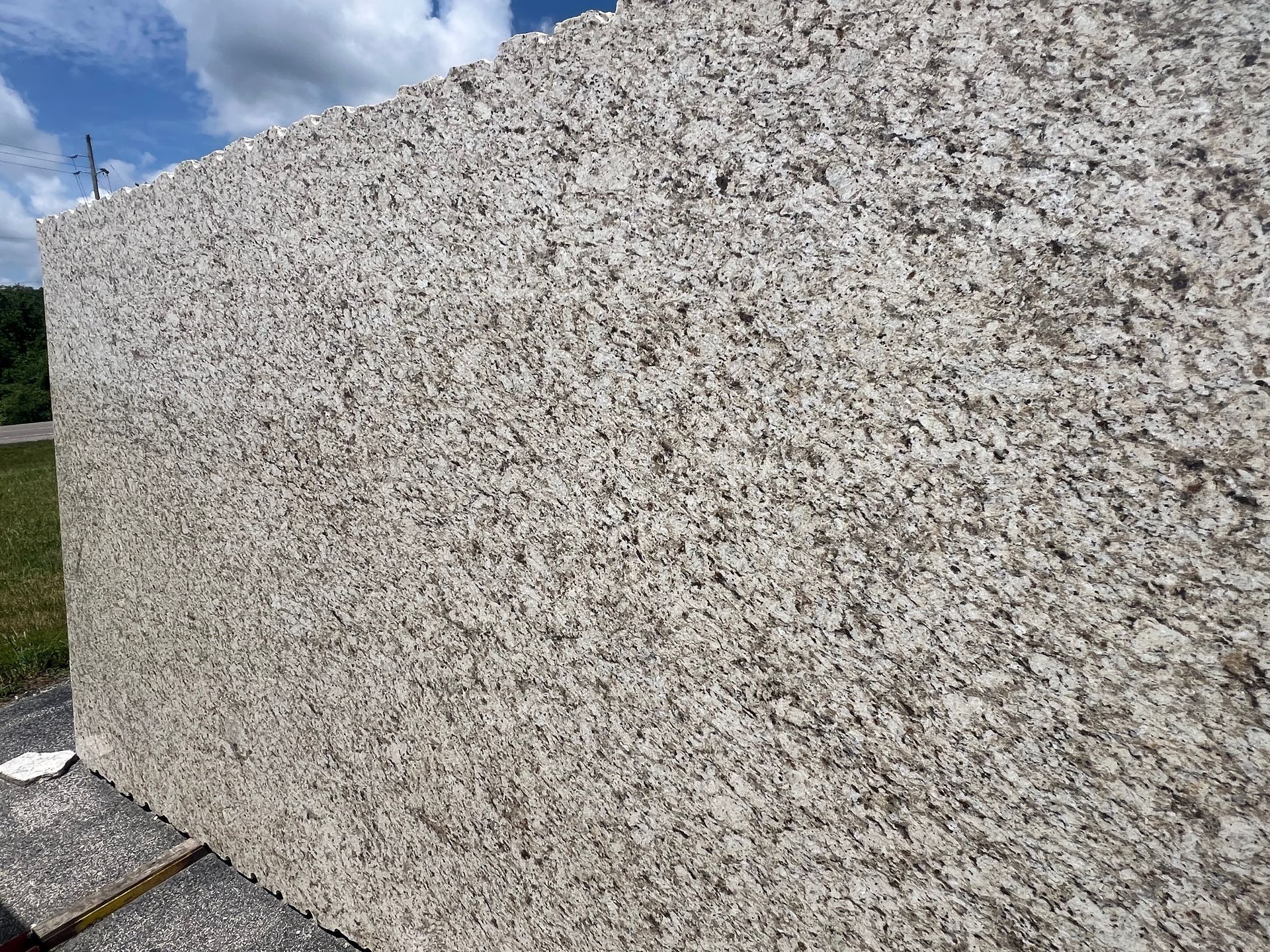 Close-up of a rough beige stone wall under a blue sky.
