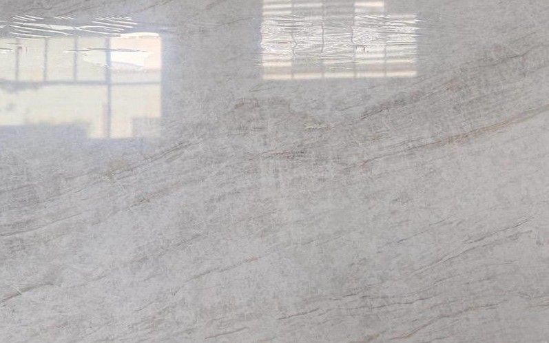 Light gray marble surface with subtle veining and reflections of windows above