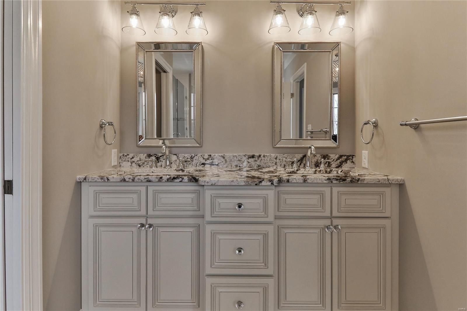 Elegant beige bathroom vanity with double mirrors, marble countertop, and wall sconces.