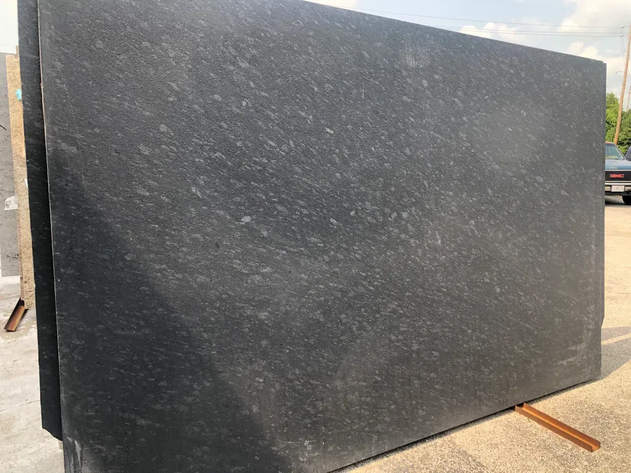 Large dark gray stone slab standing outdoors on a truck bed or loading area.
