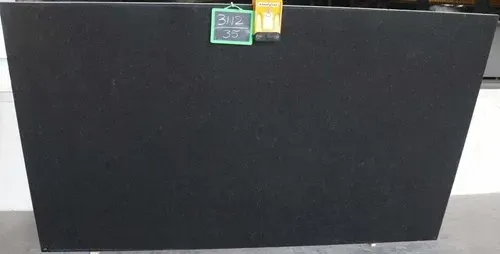 Large black rectangular board or panel against a white wall, with a small green and orange label at the top.