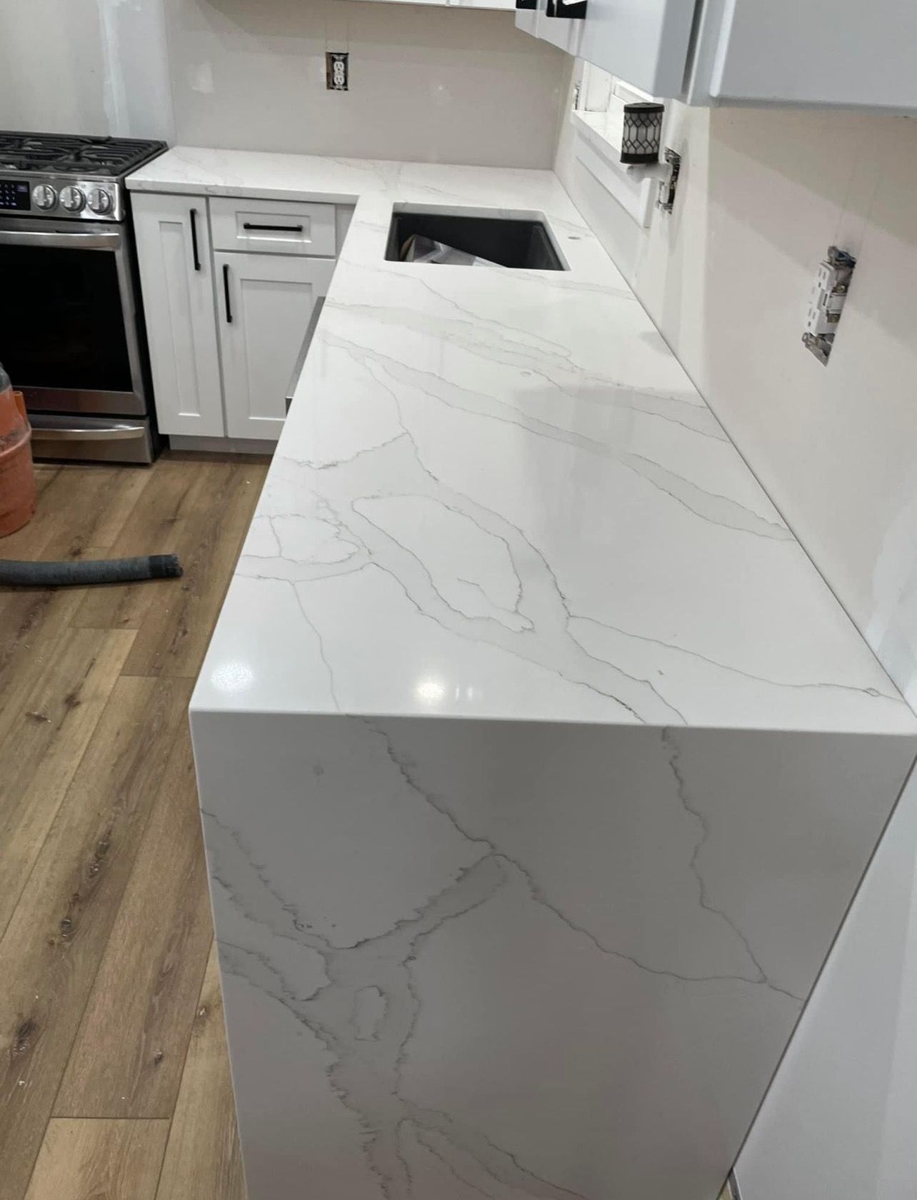 White marble-look kitchen countertop with waterfall edge and built-in sink in a modern kitchen
