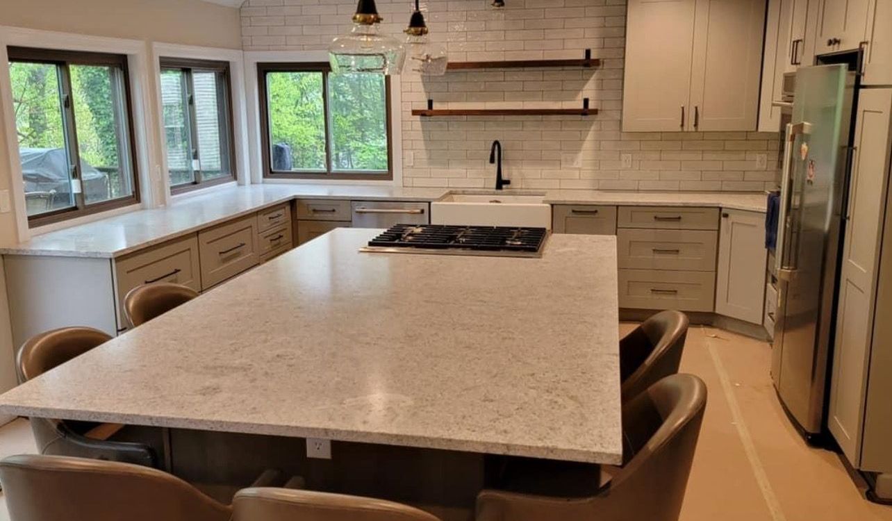 Modern kitchen with large island, white cabinets, stainless fridge, and windows over the sink