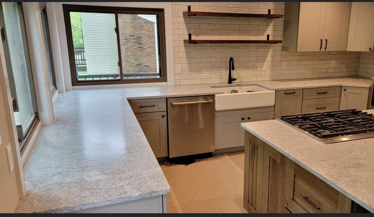 Modern kitchen with white countertops, wood cabinets, sink, dishwasher, and gas cooktop by a large window