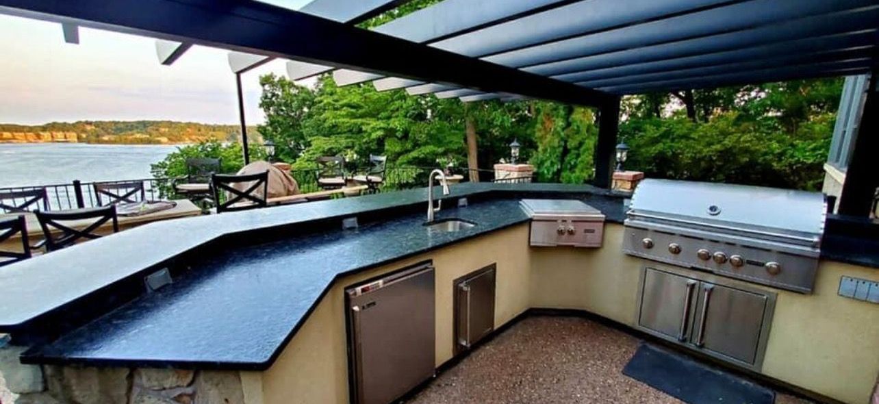 Outdoor covered patio kitchen with black countertop and marina view