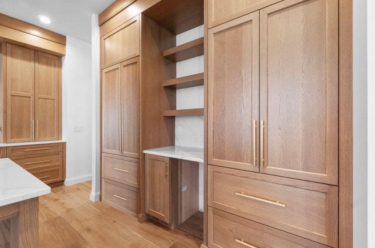 Built-in wooden closet cabinets with shelves in a bright hardwood-floored room.