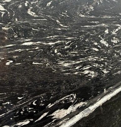 Dark black marble surface with white veining and streaks