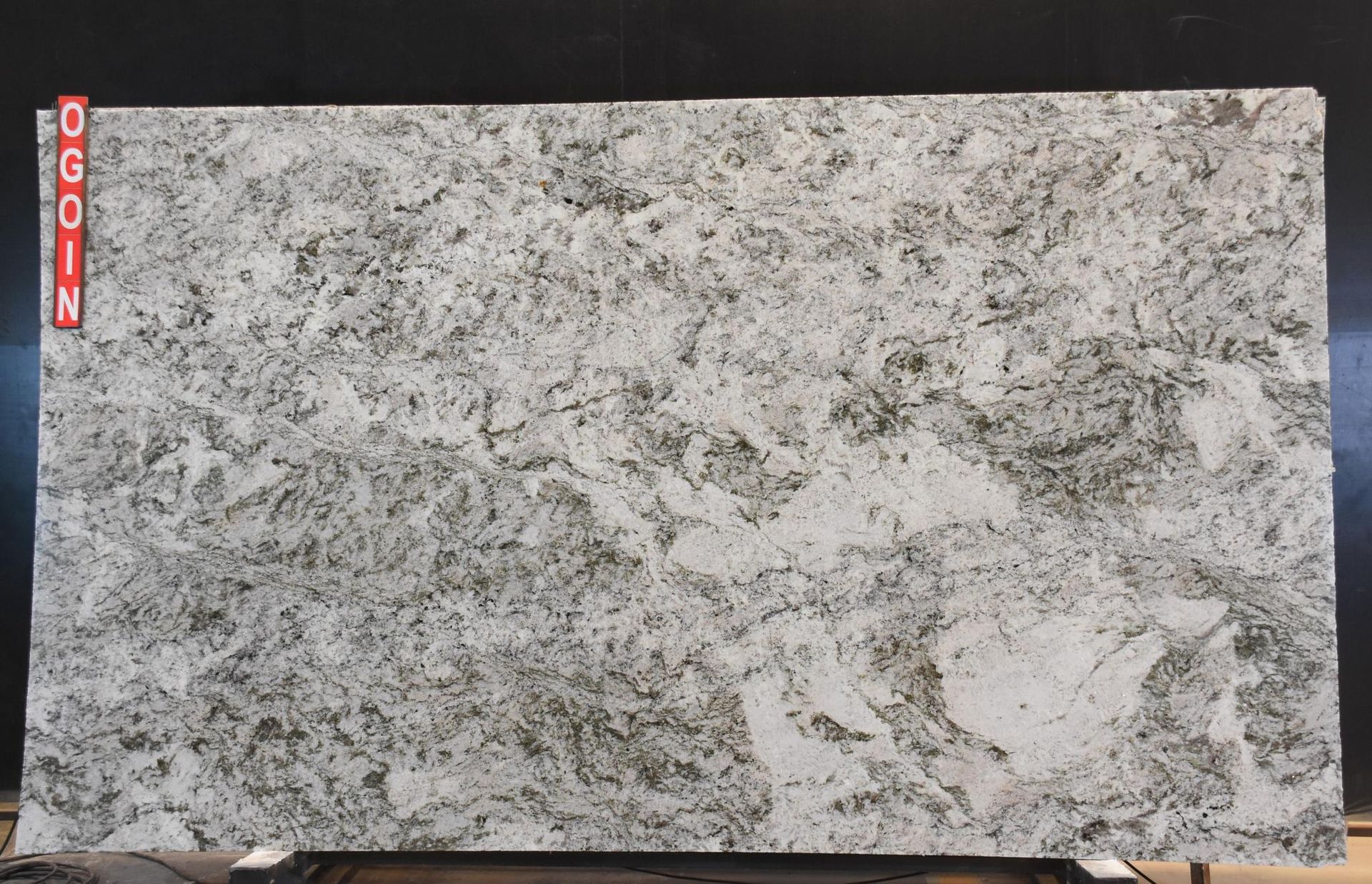 Gray speckled granite countertop slab with a red “COOK” label on the left edge