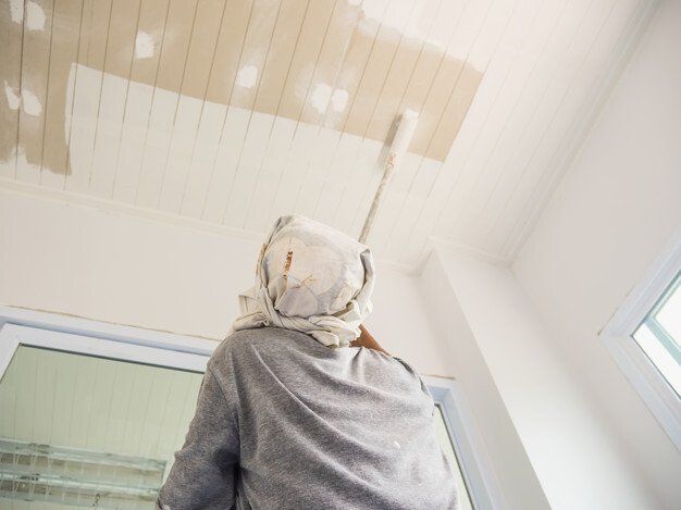 A man is painting the ceiling of a room with a brush.