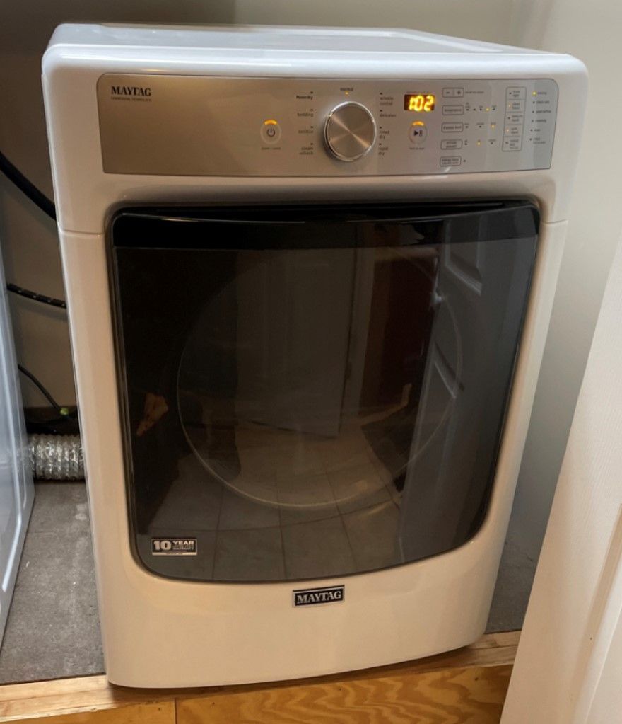 White Maytag dryer with a glass door and control panel displaying 