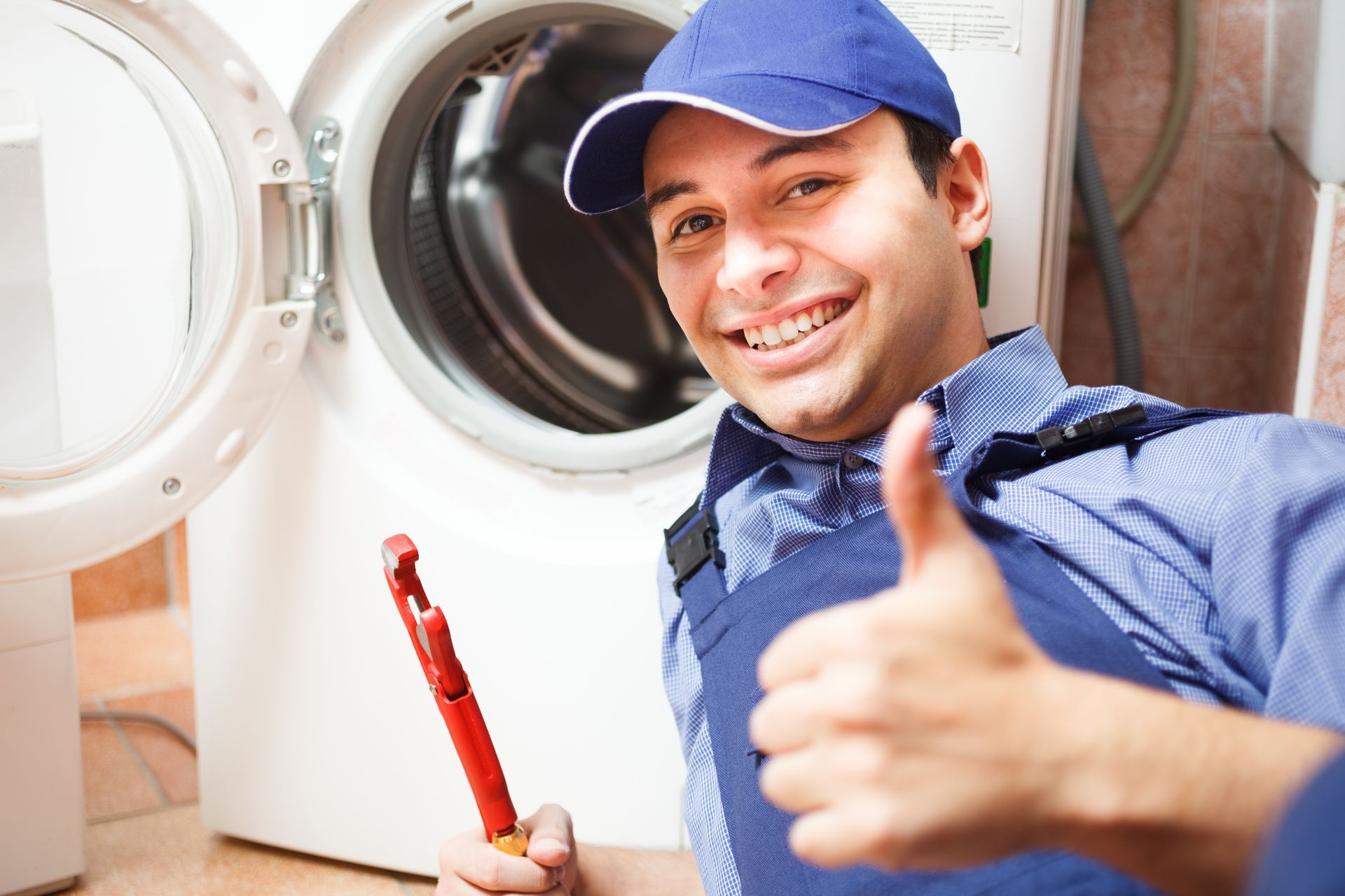 A professional appliance technician inspecting a washing machine in an Omaha, NE home.
