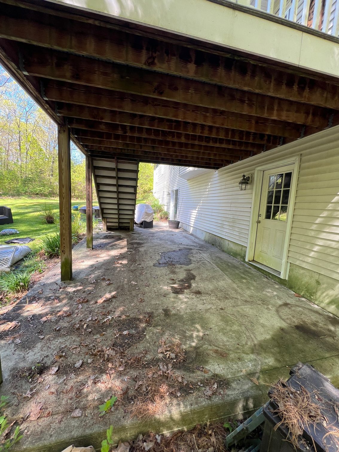 A house with a wooden deck and stairs underneath it.