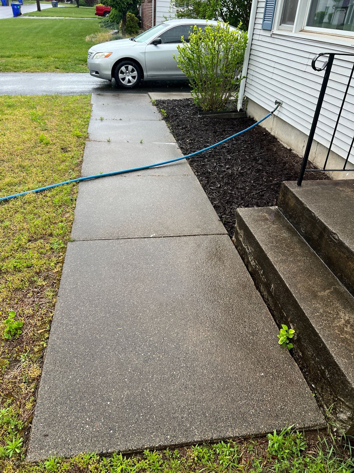 A car is parked on the sidewalk next to a house.
