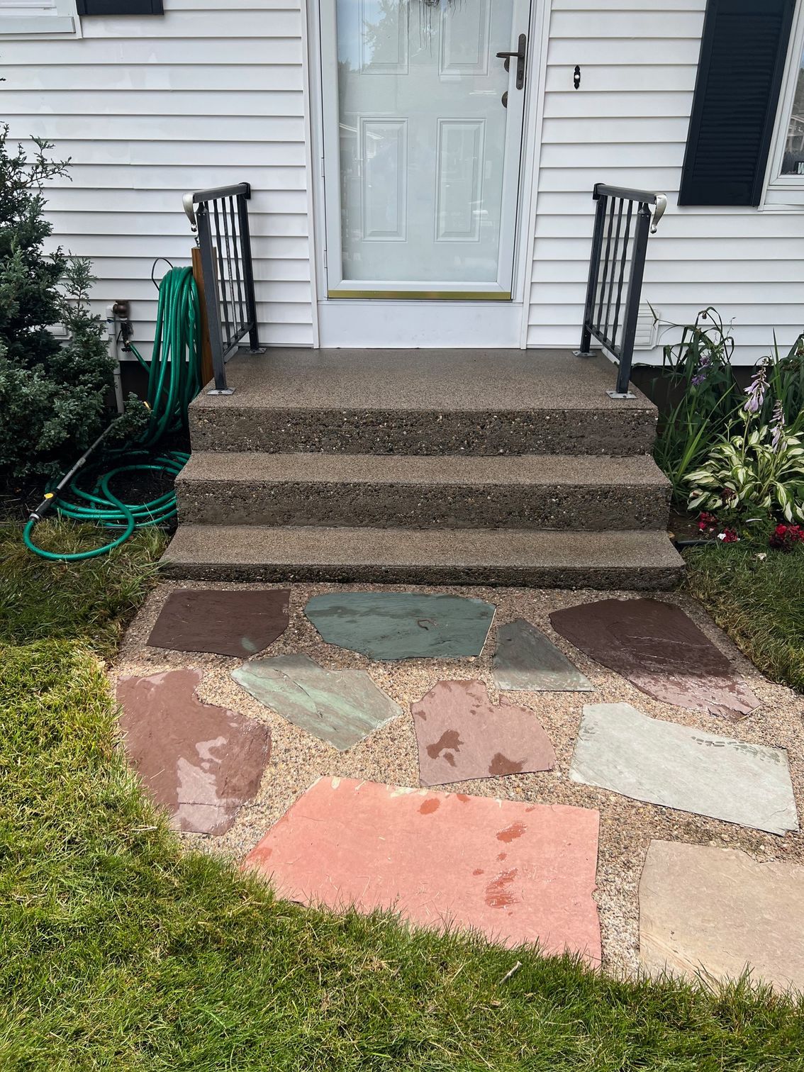 Concrete steps leading up to a white door, with a flagstone path in front.