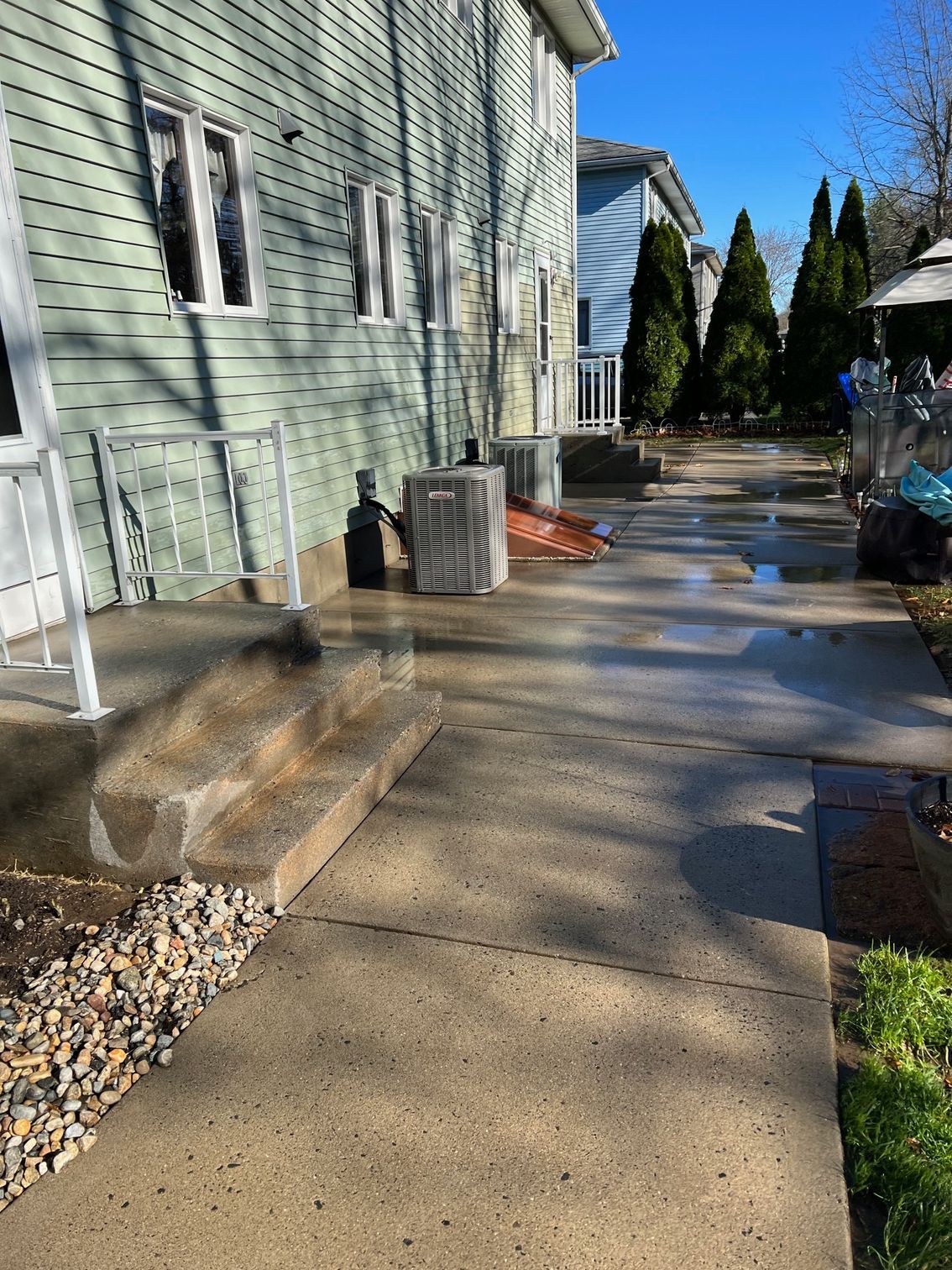 A concrete walkway leading to a house with stairs leading up to it.