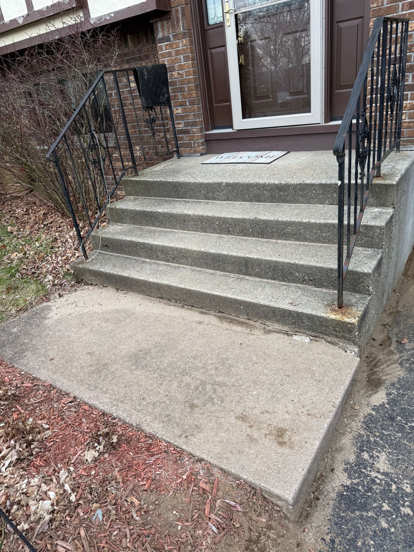 A set of stairs leading up to a house with a metal railing.