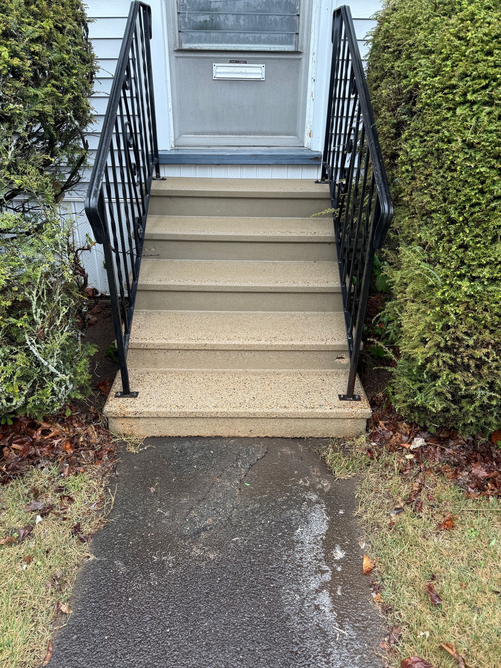 A set of stairs leading up to a house with a wrought iron railing.