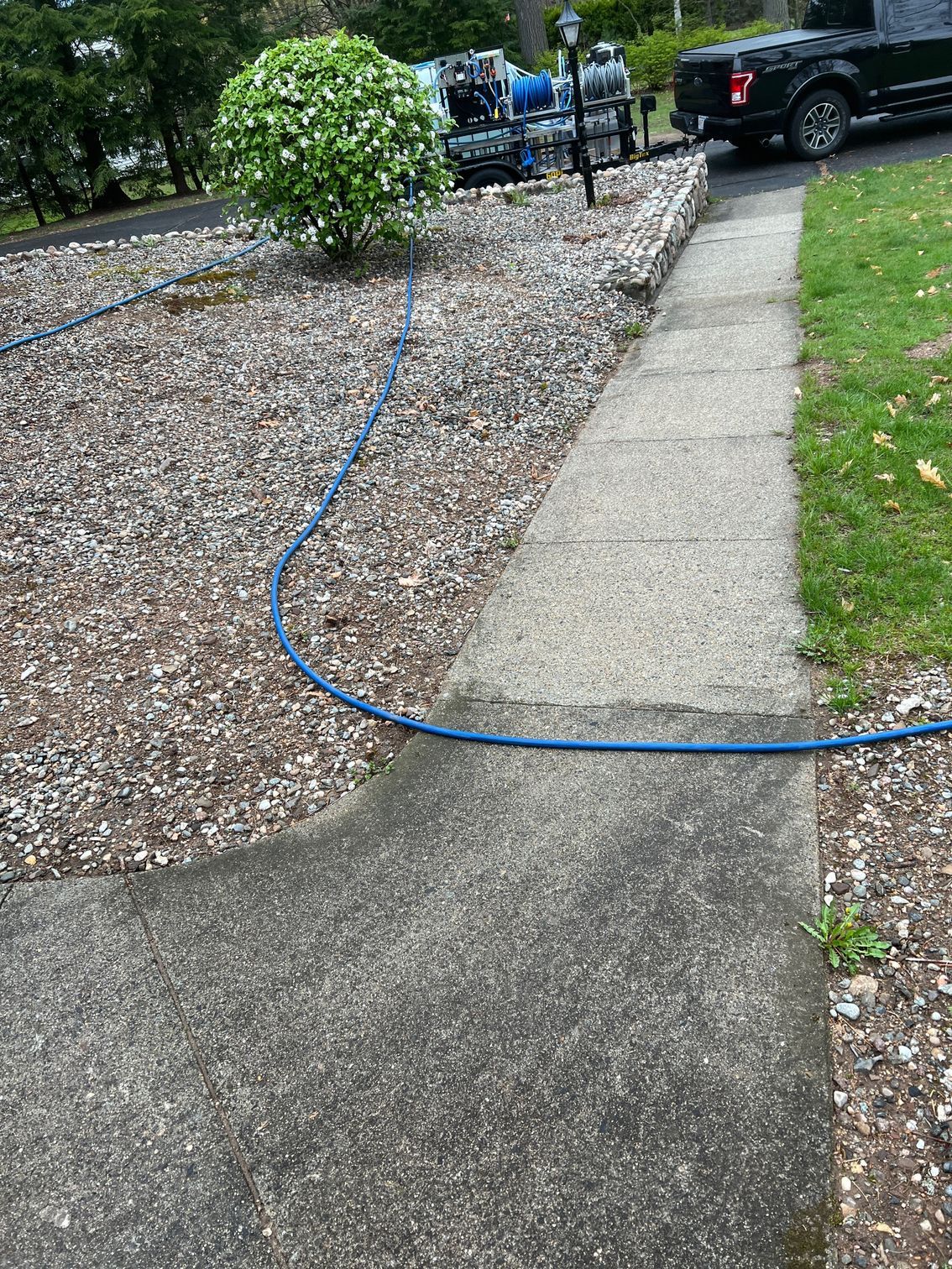 A hose is connected to a sidewalk next to a truck.