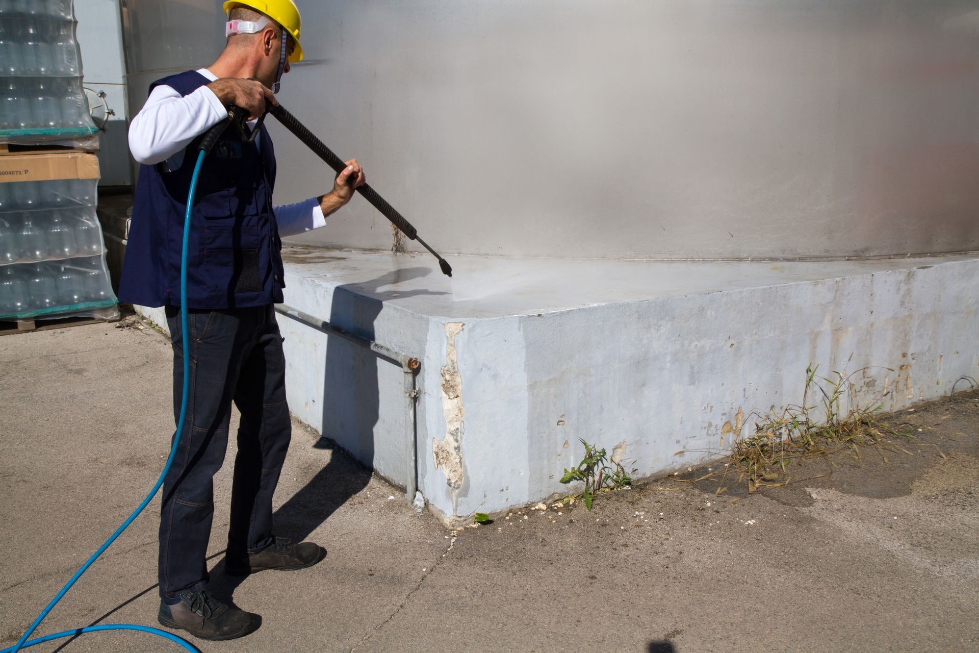 Worker pressure washing dirty clay roof tiles.