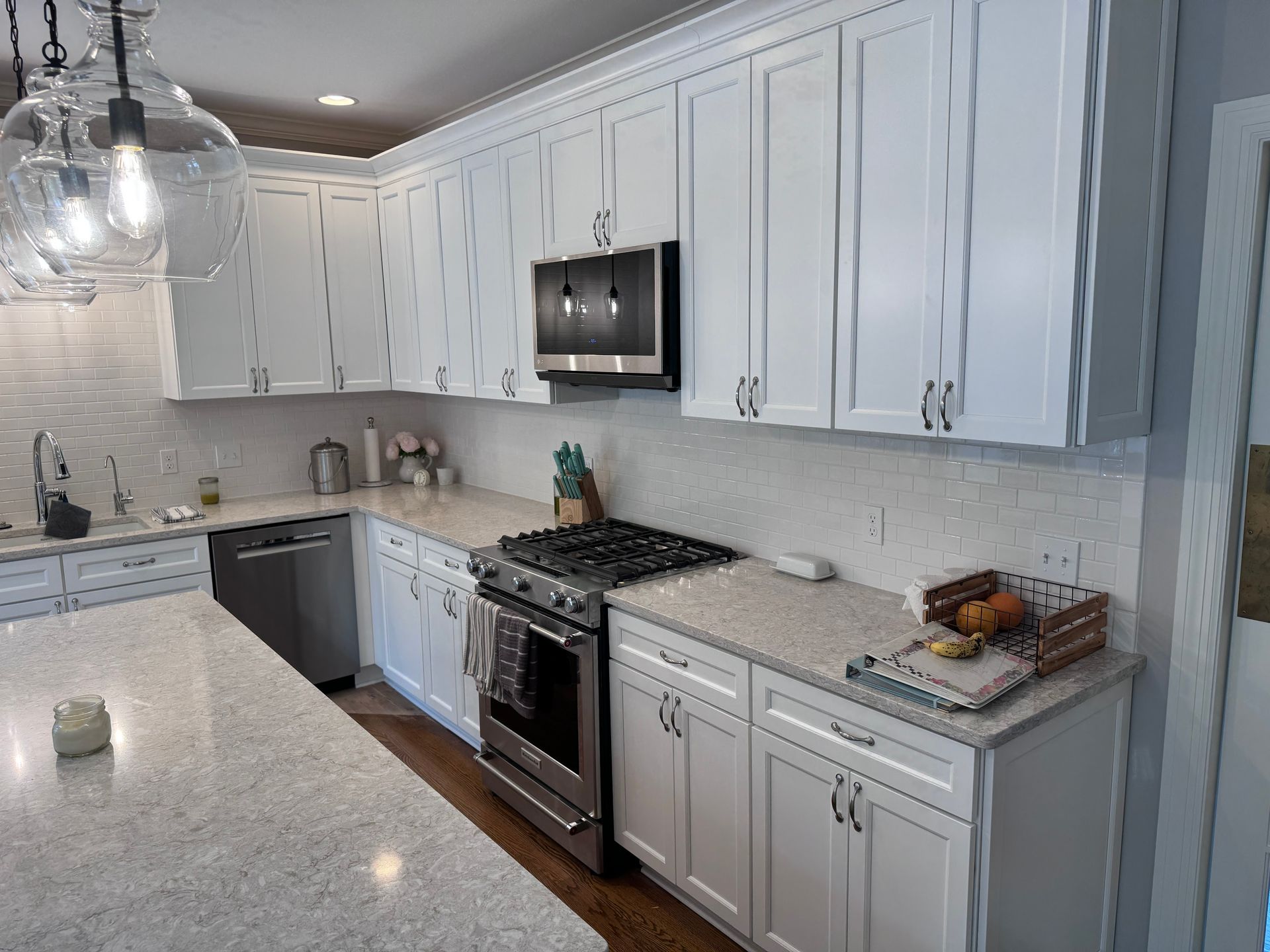 White kitchen with granite countertops, white cabinets, and stainless steel appliances.