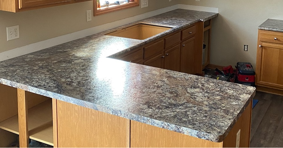 L-shaped kitchen countertop with a brown and gray speckled pattern, installed over cabinets.