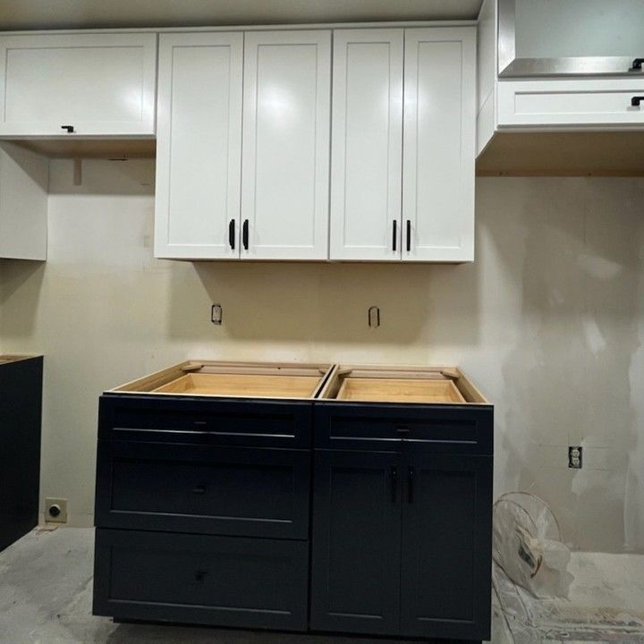 White upper kitchen cabinets over dark gray lower cabinets, under construction.