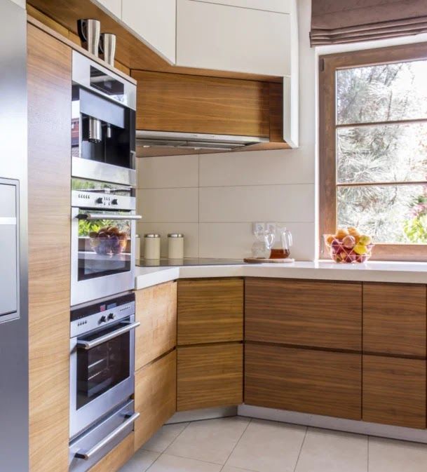 Modern kitchen with wooden cabinets, stainless steel appliances, and a window.