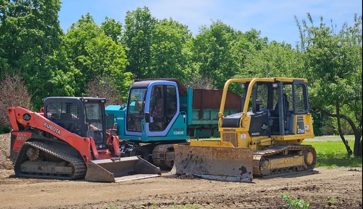Three bulldozers are parked next to each other in a dirt field.