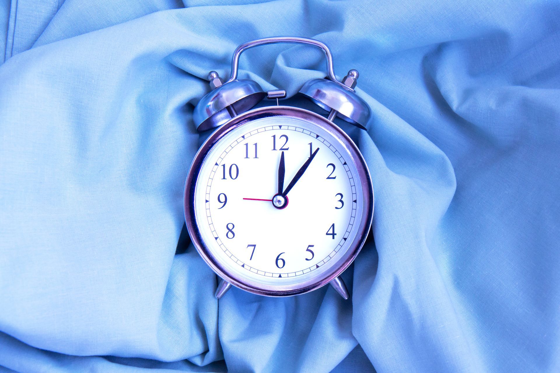 Metal clock on a blue fabric background