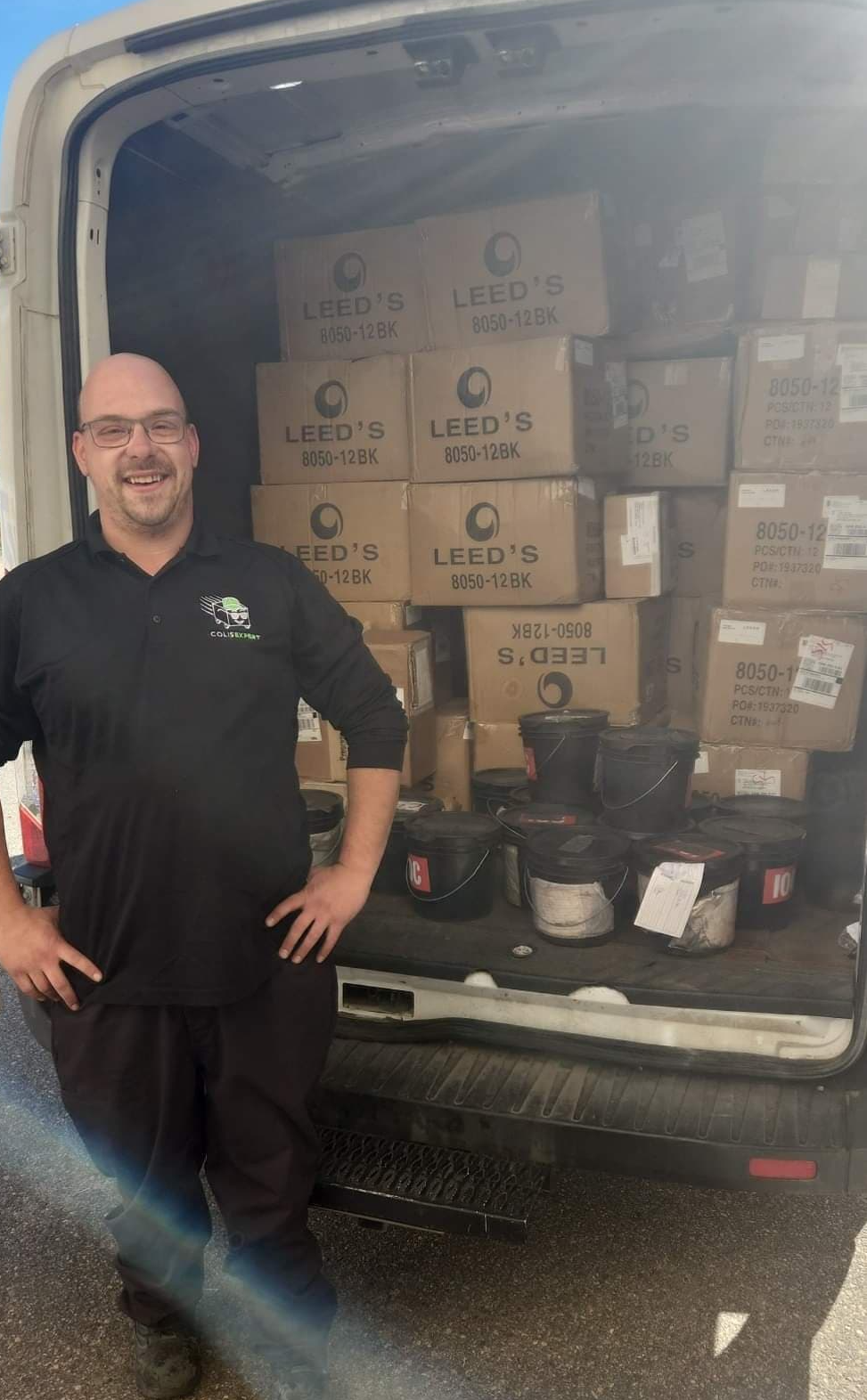 Un homme se tient à côté d'une camionnette remplie de cartons et d'articles ménagers.