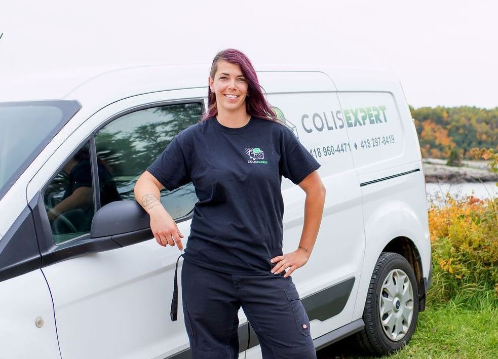 Femme debout à côté d'une camionnette blanche aux couleurs de l'entreprise, à l'extérieur sur l'herbe, souriant à la caméra