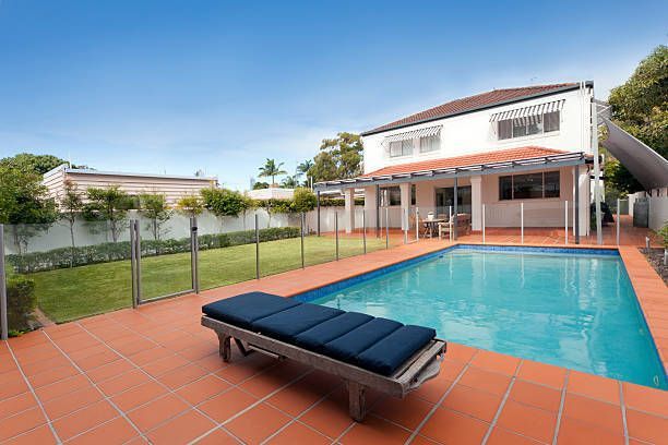 A backyard with a pool with a glass fence.