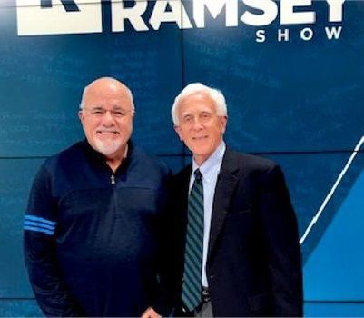 Two men standing in front of a ramsey show sign