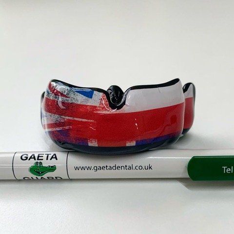Mouthguard with a Union Jack design, sitting on a pen labeled