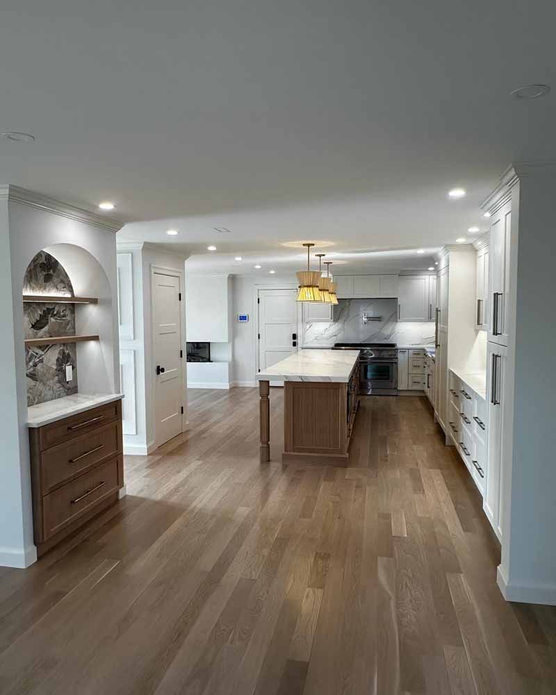 Open-concept kitchen with light wood floors, white cabinets, and a wood island.